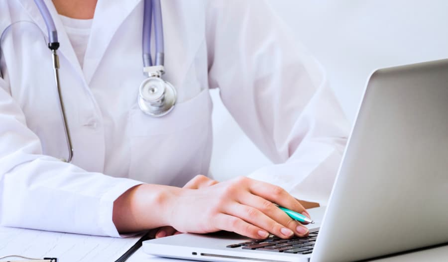 Healthcare CRM Solution - A closeup image of a doctor's hand resting on laptop