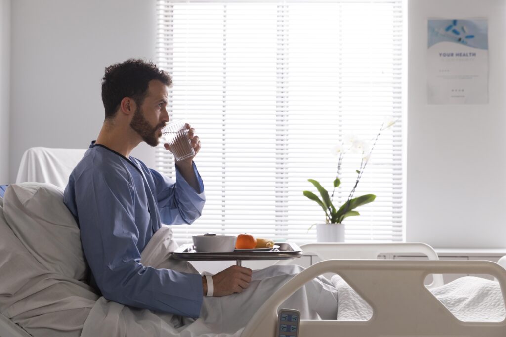 Andrology Clinics in Dubai - Male patient upright in bed drinking water 